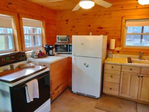 a white refrigerator in a kitchen with wooden walls at Chalet Cabin 7-Acres Pond! in Andover