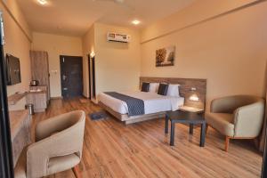 a hotel room with a bed and two chairs at Serene Aqua Hills in Kozhikode
