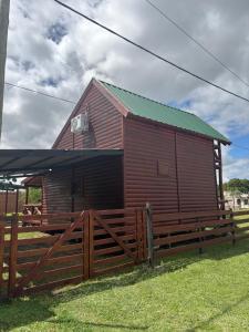 a large wooden barn with a wooden fence at Cabaña El Guayabo in Villa Urquiza