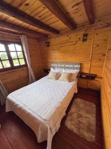 a bedroom with a bed in a wooden cabin at Cabaña El Guayabo in Villa Urquiza