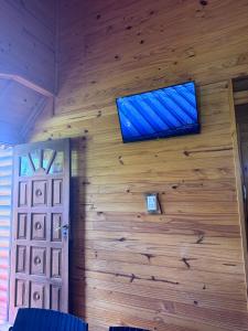 a room with a wooden wall with a television on it at Cabaña El Guayabo in Villa Urquiza