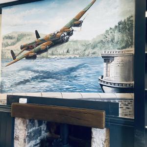 a painting of a plane flying over a river at The Ladybower Inn in Bamford