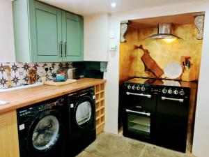 a kitchen with a washing machine and a stove at Cute Quirky Cottage in Llandow