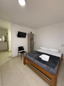 a bedroom with a bed and a tv and a chair at Apartaestudio grupal privado dentro de hotel in Medellín