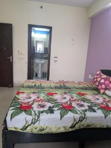 a bedroom with a bed with a floral bedspread at Panchsheel Greens 2 in Ghaziabad