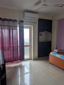 a bedroom with a bed and a large window at Panchsheel Greens 2 in Ghaziabad