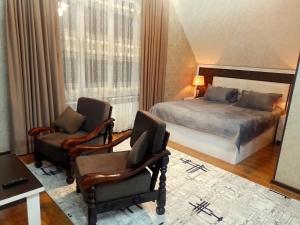 a bedroom with a bed and two chairs at Dom Semya Gusar in Qusar
