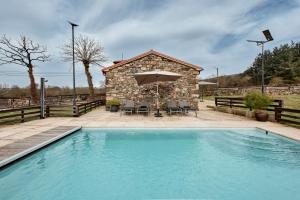 a swimming pool in front of a building with an umbrella at Casa Do Gaiteiro in Melide