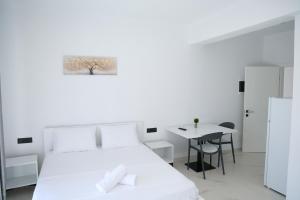a white bedroom with a white bed and a table at Vila Lori in Ksamil