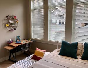 a bedroom with a bed and a desk and windows at Qualicum Landing Seaside Vill in Qualicum Beach