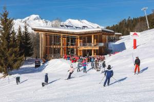 a group of people in the snow in front of a ski lodge at L'Aiguille Grive Chalets Hotel in Arc 1800