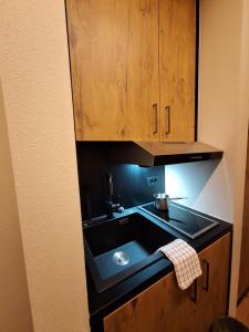 a kitchen with a sink and wooden cabinets at Green Hospitality Monolocale Stella Alpina in Livigno +12 photos