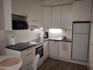 a kitchen with white cabinets and a table and a refrigerator at Easy Stay Mikkeli in Mikkeli