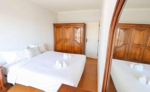 ein Schlafzimmer mit einem weißen Bett und einem Spiegel in der Unterkunft Amorosa Beach Rooftop - 400 metros da Praia in Viana do Castelo