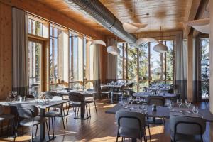 a restaurant with tables and chairs and large windows at L'Aiguille Grive Chalets Hotel in Arc 1800
