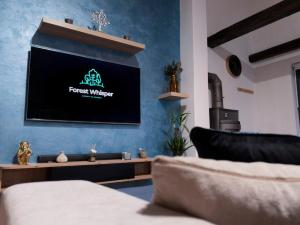 a living room with a tv on a blue wall at Forest Whisper by GoldenPinpoint in Leštakovec