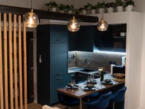a kitchen with a table with blue cabinets and lights at Forest Whisper by GoldenPinpoint in Leštakovec