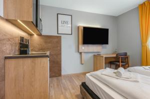 a hotel room with a bed and a kitchen and a tv at RENOVIERT XZLLENZ 50'' Smart TV, Parken, 24h digitaler Check In und Zugang, Küche in Oberasbach
