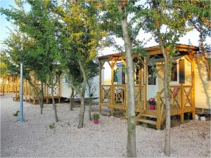 a yellow house with trees in front of it at Mobile Homes Peroš in Zaton