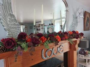 a mantle with flowers and a clock on it at Cute Quirky Cottage in Llandow
