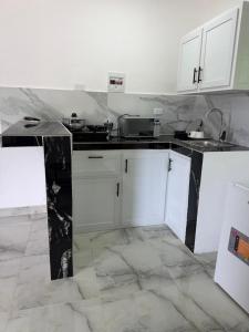 a kitchen with white cabinets and black counter tops at Brisas del mar 2c in Santa Cruz de Barahona