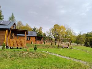 a log cabin with a playground and a swing at Domki Tepakówka in Wołkowyja