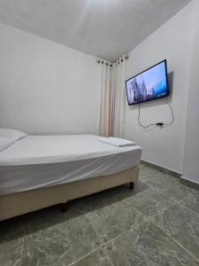 a bedroom with a bed with a tv on the wall at La Tribuna Lounge in Valledupar