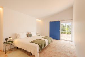 a bedroom with a large bed with a blue door at Monte da Torre in Tavira +26 photos