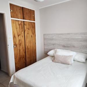 a bedroom with a white bed with a wooden door at Duplex Parking free in Estación Circunvalación