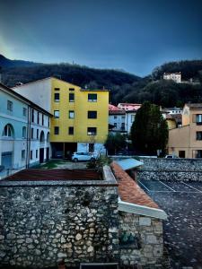 a yellow building sitting on top of a stone wall at A Casa di Angelica in Piovene Rocchette