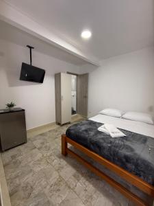 a bedroom with a bed and a tv on the wall at Apartaestudio grupal privado dentro de hotel in Medellín