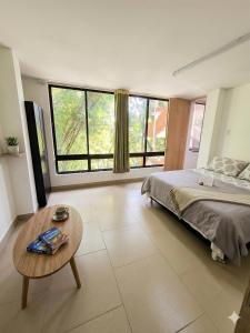 a bedroom with a bed and a table and windows at Pilarica Gardens in Medellín