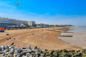 a beach with people sitting on the sand and a bird flying at My Spacious Kentish 3-Room Van in Birchington