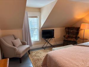 a bedroom with a bed and a chair and a television at My Valhalla Farm in Oakland