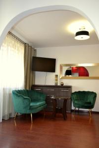 a living room with two green chairs and a television at Apartament Piast w Rynku in Nysa