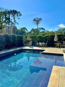 a swimming pool with chairs and tables in a yard at Chalé Shanti in Resende