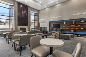 a waiting room with tables and chairs and a fireplace at Best Western Plus Elgin - Chicago in West Dundee
