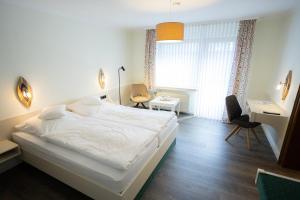 a bedroom with a white bed and a desk at Hotel Bischof in Schmallenberg +32 photos
