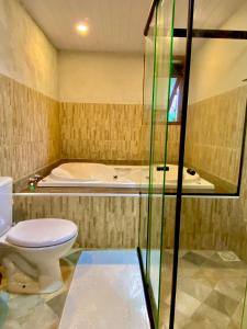 a bathroom with a toilet and a bath tub at Chalé Shanti in Resende