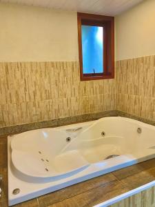 a large bath tub in a bathroom with a window at Chalé Shanti in Resende