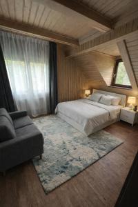 a bedroom with a bed and a couch and a window at Everwood Lodge, Transylvania in Sub Cetate