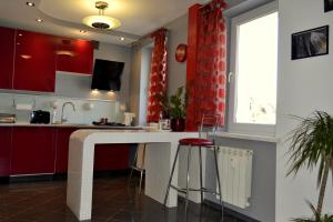 a kitchen with red cabinets and a counter with stools at Apartament Piast w Rynku in Nysa