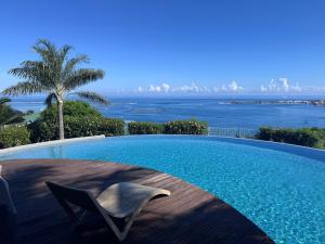 a swimming pool with a chair and the ocean at Your Tahiti Escape in Faaa