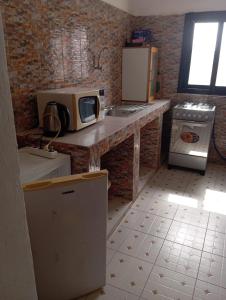 a kitchen with a counter with a microwave and a stove at Keur Vieux DIATTA in Ziguinchor +2 photos