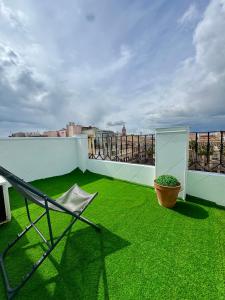a balcony with green grass and a chair on a roof at Mini Estudio Málaga in Málaga