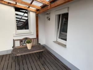 a wooden bench sitting on a porch with two windows at Arcadia in Remagen