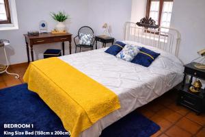 a bedroom with a bed with a yellow blanket on it at Prédio do Castelo in Caloura