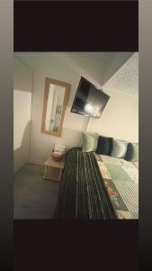 a bedroom with a bed and a tv on the wall at The Cosy Cumbrian Homestay in Penrith