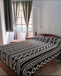 a bed with a black and white comforter and a window at Hostel Las Lengas in Buenos Aires +15 photos