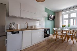a kitchen with white cabinets and a table with chairs at Apartament Miętowy Kwidzyn in Kwidzyn